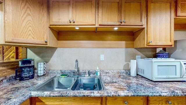 kitchen with tasteful backsplash, sink, and light stone countertops