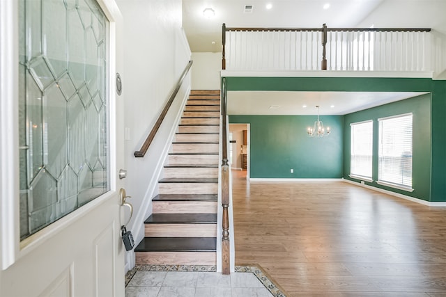 stairway with hardwood / wood-style flooring, a notable chandelier, and a towering ceiling