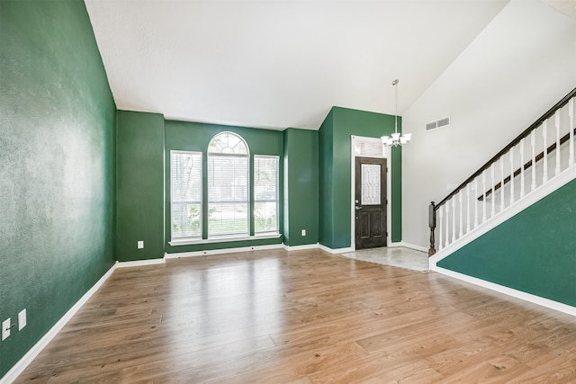 entrance foyer featuring high vaulted ceiling, a chandelier, and wood-type flooring