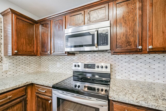 kitchen featuring decorative backsplash, light stone counters, and stainless steel appliances