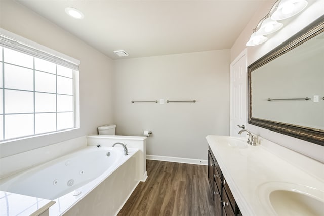 bathroom with wood-type flooring, toilet, double vanity, and a tub to relax in