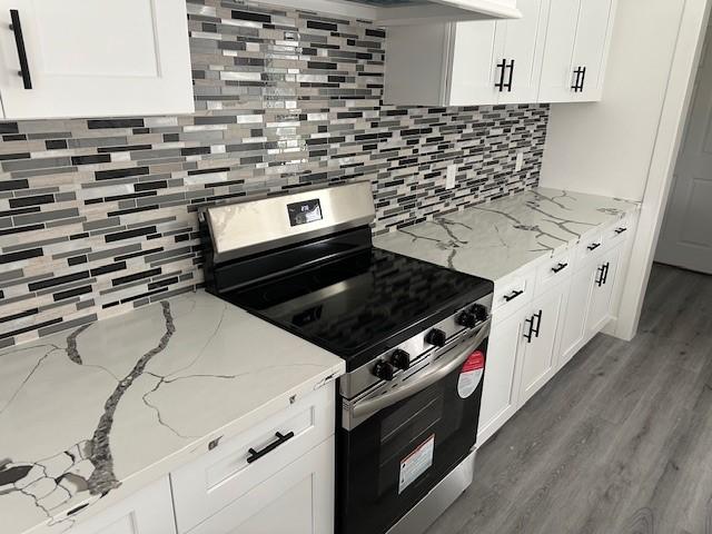 24629 Waterford St, Hempstead, TX 77445 - kitchen with backsplash, wood finished floors, stainless steel range with electric stovetop, and white cabinets