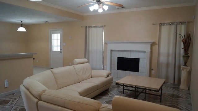 living room featuring ceiling fan, a tiled fireplace, and ornamental molding