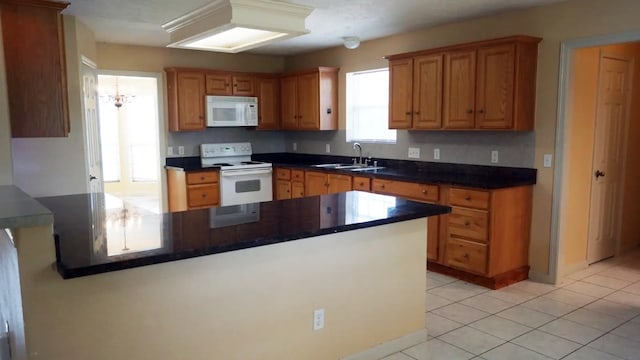 kitchen featuring light tile patterned flooring, sink, kitchen peninsula, and white appliances