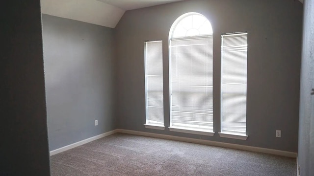 carpeted spare room with lofted ceiling