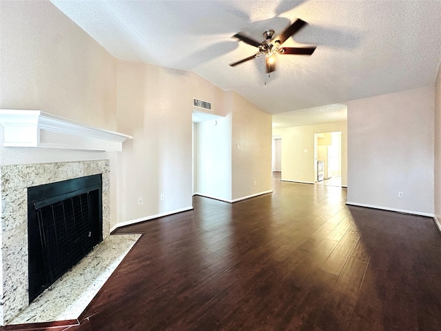 unfurnished living room with ceiling fan, a premium fireplace, wood finished floors, visible vents, and vaulted ceiling