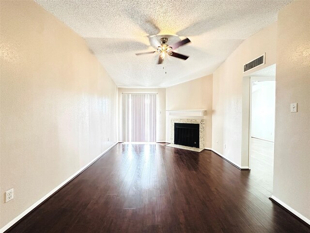 unfurnished living room with ceiling fan, a fireplace with flush hearth, visible vents, baseboards, and dark wood finished floors