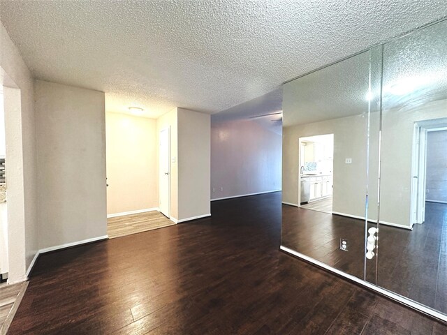 unfurnished room featuring a textured ceiling, baseboards, and hardwood / wood-style floors