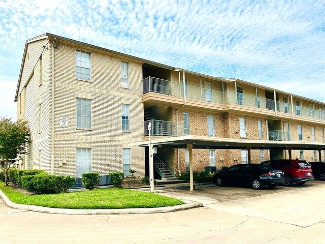 view of building exterior featuring covered parking, cooling unit, and stairs