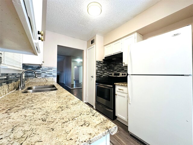 kitchen with stainless steel stove, tasteful backsplash, white refrigerator, white cabinets, and sink