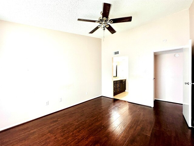 unfurnished bedroom featuring hardwood / wood-style floors, a high ceiling, connected bathroom, a textured ceiling, and ceiling fan