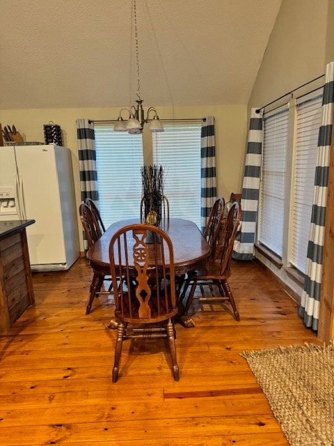 dining area featuring light hardwood / wood-style floors, lofted ceiling, and a chandelier