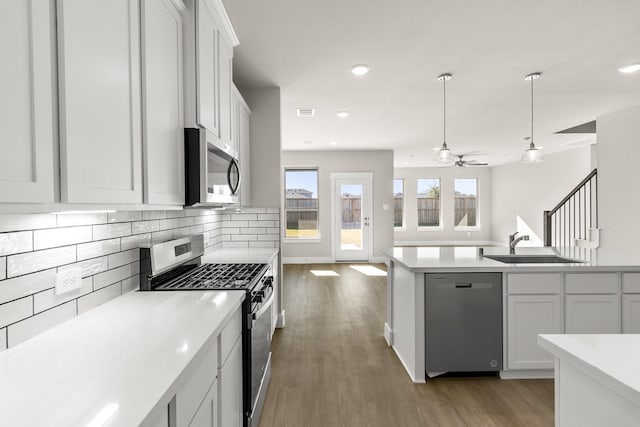 kitchen featuring decorative backsplash, stainless steel appliances, ceiling fan, sink, and white cabinetry