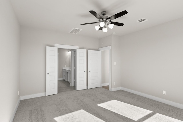 unfurnished bedroom featuring ensuite bath, ceiling fan, and light colored carpet