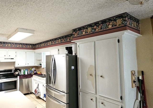 kitchen featuring a textured ceiling, stainless steel appliances, and light tile patterned flooring