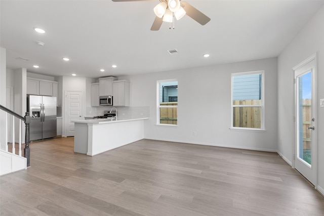 kitchen featuring light wood-type flooring, kitchen peninsula, stainless steel appliances, and a wealth of natural light