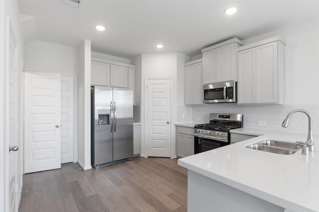 kitchen with appliances with stainless steel finishes, sink, backsplash, light hardwood / wood-style floors, and white cabinets