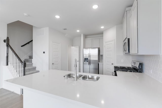 kitchen with sink, stainless steel appliances, white cabinetry, and kitchen peninsula