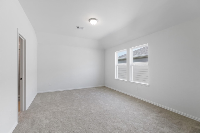 spare room featuring vaulted ceiling and light colored carpet