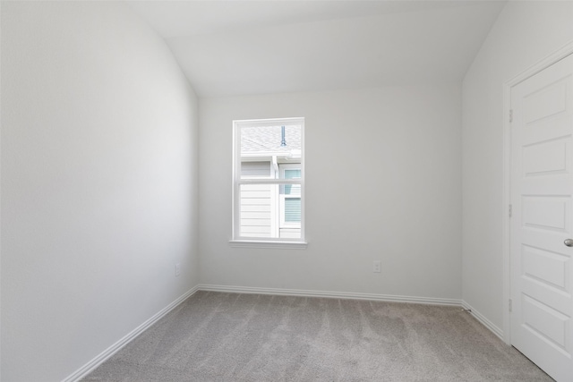 empty room with vaulted ceiling and light colored carpet