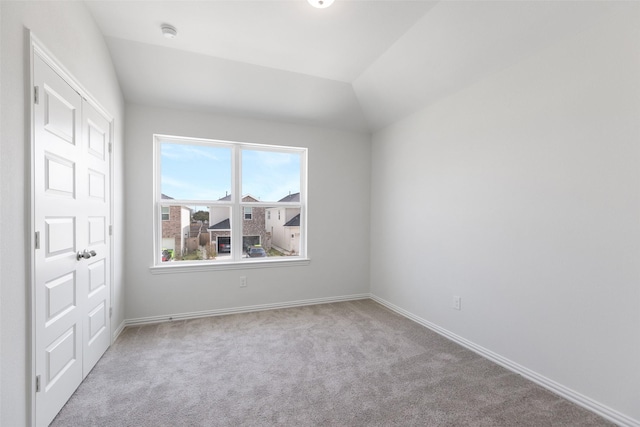 carpeted spare room featuring vaulted ceiling