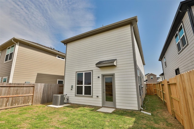 rear view of house featuring cooling unit and a yard