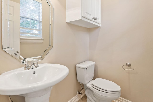 bathroom featuring toilet, baseboards, and a sink