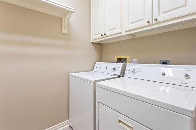 clothes washing area with cabinet space, baseboards, and washer and clothes dryer