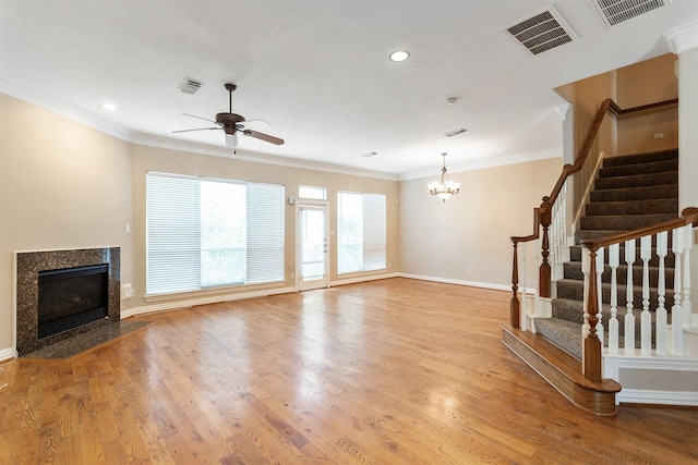 unfurnished living room with ornamental molding, wood finished floors, visible vents, and a high end fireplace