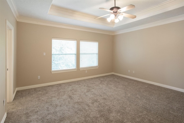 carpeted spare room featuring baseboards, ceiling fan, a tray ceiling, and crown molding