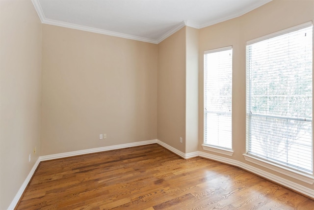 spare room with ornamental molding, baseboards, and wood finished floors