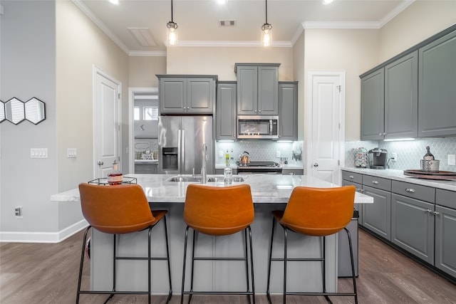 kitchen featuring stainless steel appliances, tasteful backsplash, dark hardwood / wood-style flooring, and an island with sink