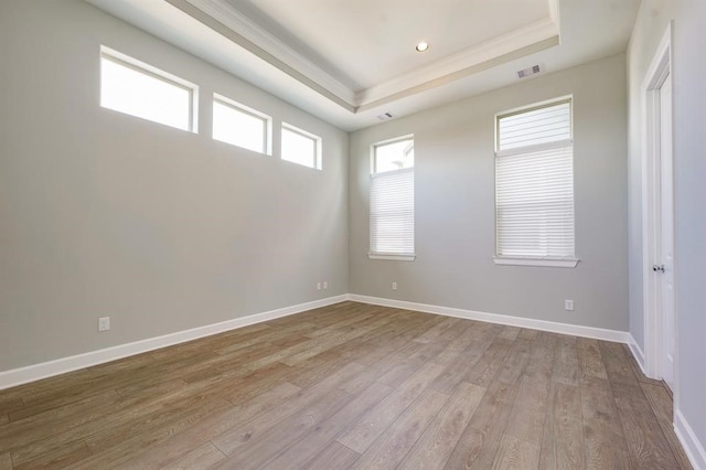 unfurnished room with hardwood / wood-style flooring and a tray ceiling