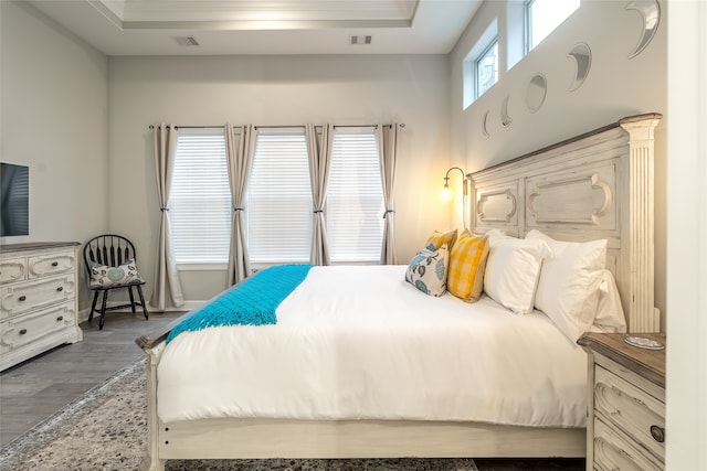 bedroom with hardwood / wood-style floors and a tray ceiling