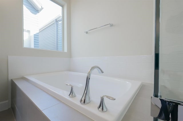 bathroom with a tub to relax in and tile walls