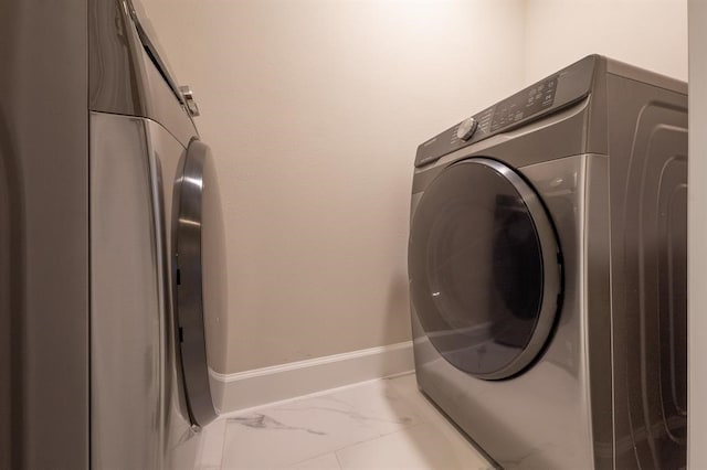 laundry area with separate washer and dryer and light tile patterned floors