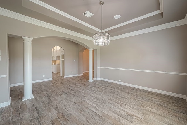 unfurnished room with light hardwood / wood-style floors, a chandelier, decorative columns, and a tray ceiling