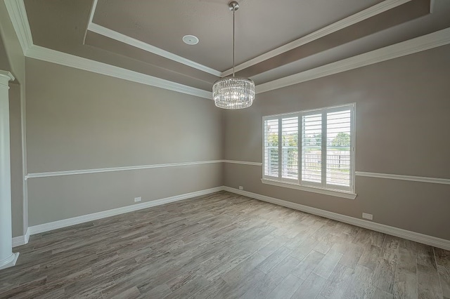 unfurnished room featuring a notable chandelier, a raised ceiling, crown molding, and wood-type flooring