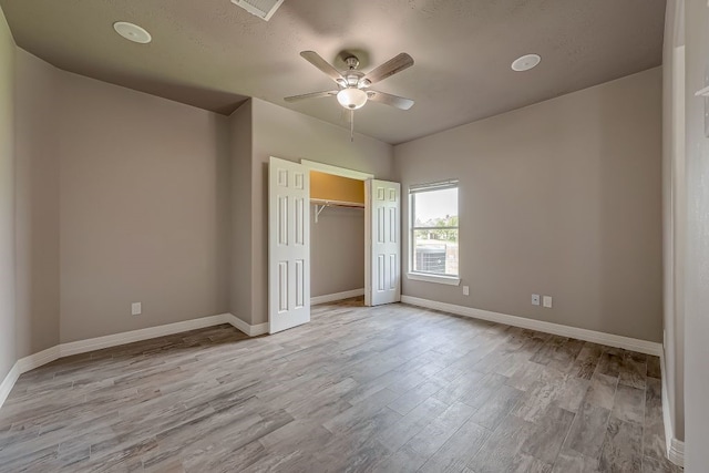 unfurnished bedroom with ceiling fan, a closet, and light hardwood / wood-style floors