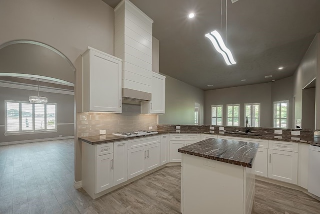 kitchen with decorative light fixtures, kitchen peninsula, a healthy amount of sunlight, and a kitchen island