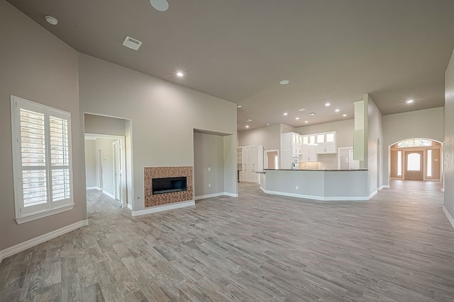 unfurnished living room featuring light hardwood / wood-style floors and a towering ceiling