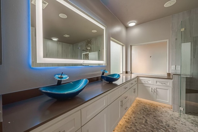 bathroom with tile patterned flooring, double sink vanity, and a shower with shower door