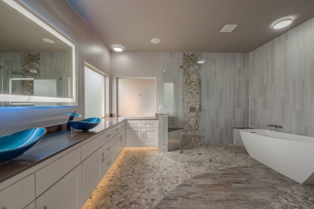 bathroom featuring tile walls, tile patterned flooring, double vanity, and a shower