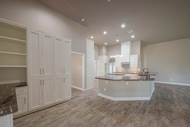 kitchen featuring decorative backsplash, light hardwood / wood-style flooring, a kitchen island, white cabinetry, and sink