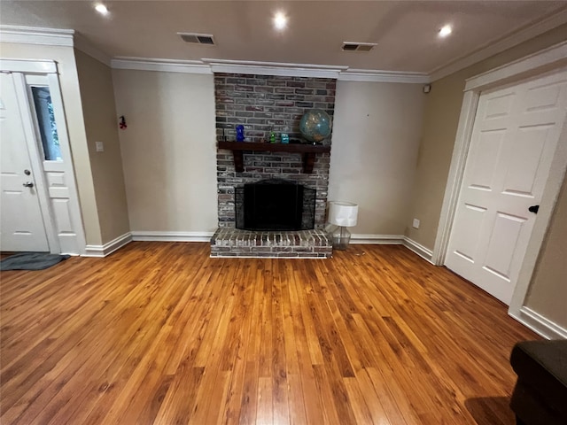 unfurnished living room featuring a brick fireplace, ornamental molding, and light hardwood / wood-style flooring