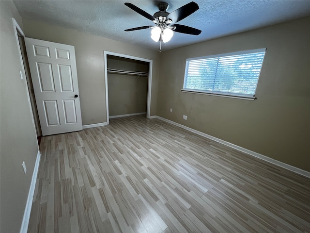 unfurnished bedroom with ceiling fan, light wood-type flooring, a textured ceiling, and a closet