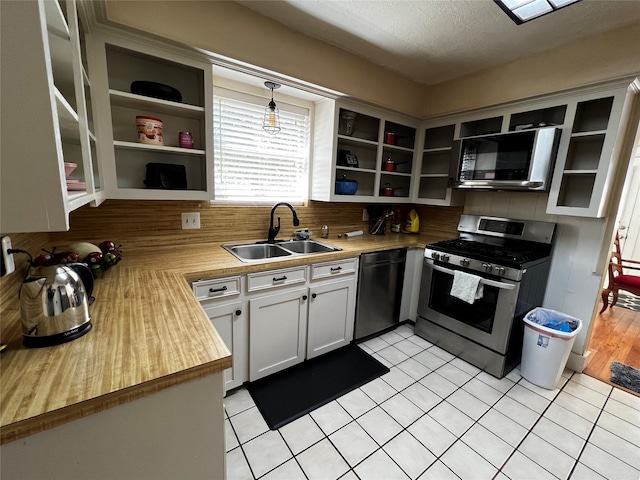 kitchen featuring a textured ceiling, sink, black appliances, white cabinets, and hanging light fixtures