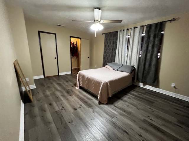 bedroom with hardwood / wood-style floors, ceiling fan, a walk in closet, and a closet