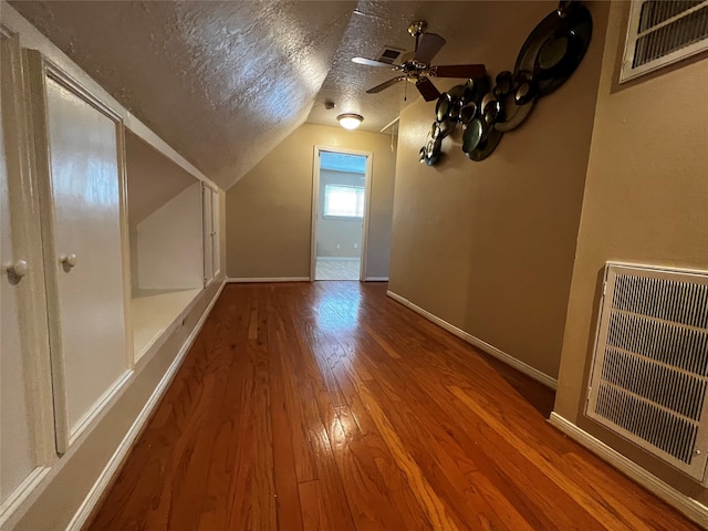 additional living space featuring hardwood / wood-style floors, a textured ceiling, vaulted ceiling, and ceiling fan