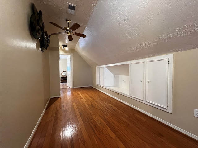 additional living space with a textured ceiling, vaulted ceiling, light hardwood / wood-style flooring, and ceiling fan